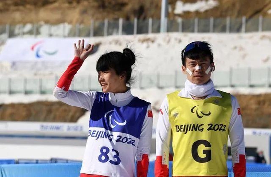  △3月8日，在残奥冬季两项女子中距离（视障）比赛后，王跃（左）向现场观众致意。