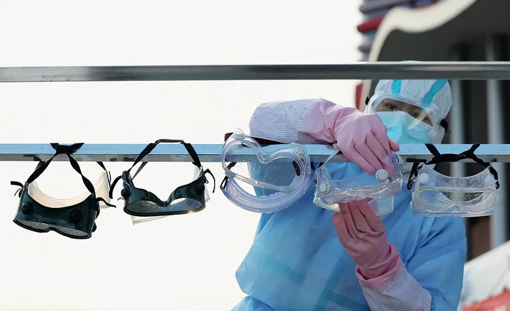 2月18日，武汉客厅方舱医院外，一名护士正在晾晒用消毒液浸泡过的护目镜。摄影/长江日报 陈卓