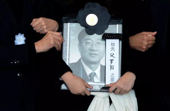  2012年11月29日，追悼会，罗阳的女儿抱着父亲遗像