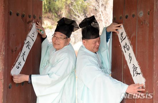 汉字对联:韩国人提前庆祝立春:贴汉字对联 白纸黑字亮了 儒生们将对联贴在门上。(纽西斯通讯社)