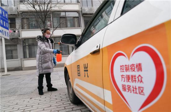 1月27日，武汉市武昌区粮道街昙华林社区干部在给配给社区使用的出租车消毒。新华社记者 程敏 摄