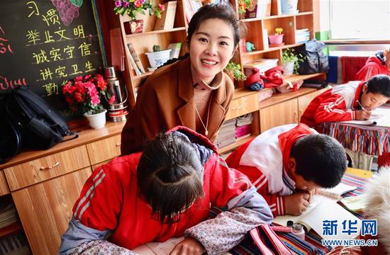  在西藏拉萨的一所小学，参加大学生志愿服务西部计划的上海交通大学博士生梁晴雪在帮学生们辅导功课（2019年3月23日摄）。 新华社发