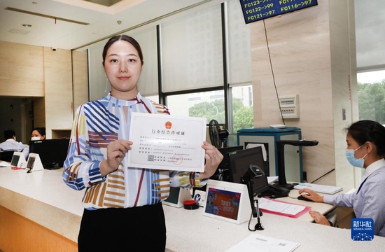 　　一家主营便利店业务的商贸公司工作人员在上海市浦东新区企业服务中心办事大厅展示新申领的行业综合许可证（2020年8月4日摄）。新华社记者 方喆 摄