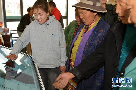 4月27日，在西藏山南市加查县冷达乡共康村电商服务站，工作人员白玛卓嘎（左前）向村民介绍电商服务。新华社记者 张汝锋 摄