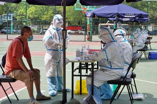 北京市丰台区东高地街道社区卫生服务中心的医护人员在高温下为居民进行采样（6月15日摄）。新华社记者 李欣 摄