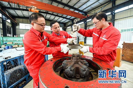 在中国石化江苏油田工程技术服务中心，田明（中）与团队工作人员在保养设备（10月9日摄）。新华社记者 李博 摄