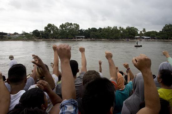 来自洪都拉斯的民众站在洪墨边境河前，望着自己的家乡（美联社）