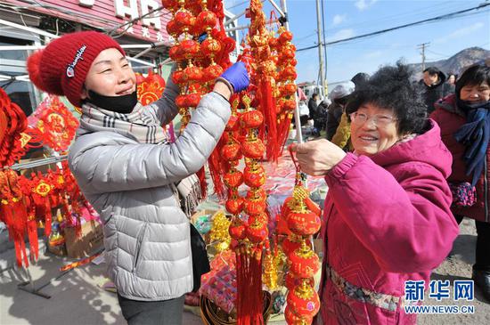 1月15日，市民在山东青岛沙子口年货大集上选购春节挂饰。春节临近，各地商贸、年货集市日渐火爆，年味越来越浓。新华社发（王海滨 摄）