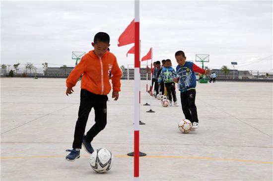 　在武威市古浪县黄花滩生态移民区富民新村富民小学，足球兴趣小组的孩子们开展训练（8月22日摄）。新华社记者 范培珅 摄