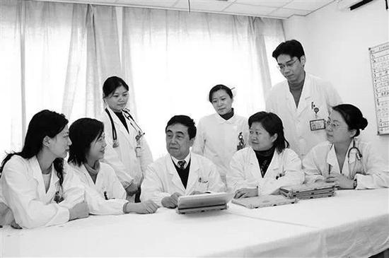 钱家麒教授（中间）与科室同事、学生在一起交流。上海交大医学院附属仁济医院 供图