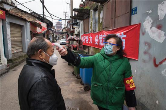 武汉西城壕社区网格员曹岚英（右）为居民测量体温（2月7日摄）。新华社记者 肖艺九 摄
