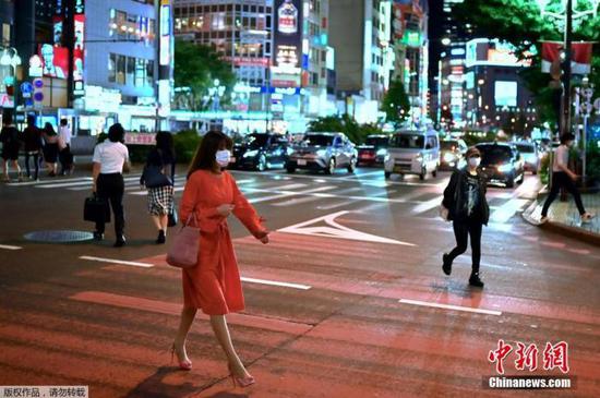 当地时间5月25日，东京新宿区，一名戴口罩的妇女穿过街道。