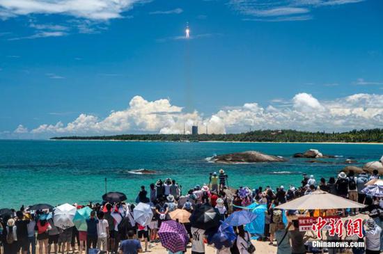 图为民众在海边观看长征五号遥四火箭发射升空。 骆云飞 摄