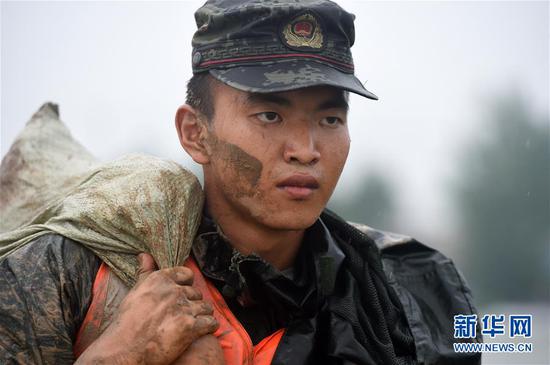 7月18日，在位于安徽省和县黄坝村的石跋河堤坝上，武警战士搬运沙袋。 新华社记者 周牧 摄