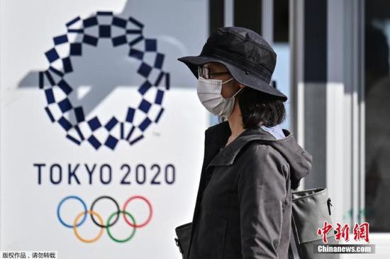 资料图为一名女士走过2020年东京奥运会海报。
