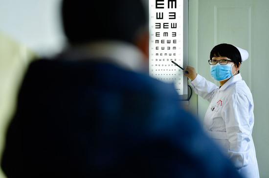 12月16日，海东市第二人民医院眼科护士许国娟在给患者检查视力。