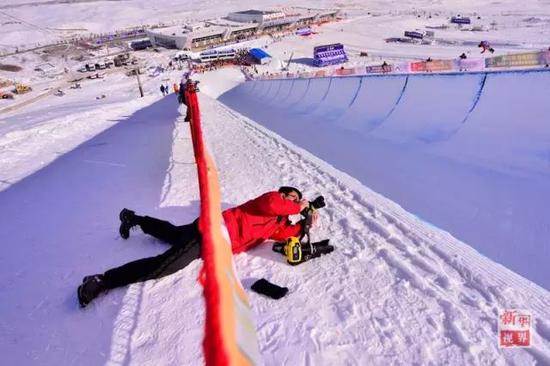 新华社记者陈斌在全国冬运会上趴在雪地里拍摄U型槽比赛。