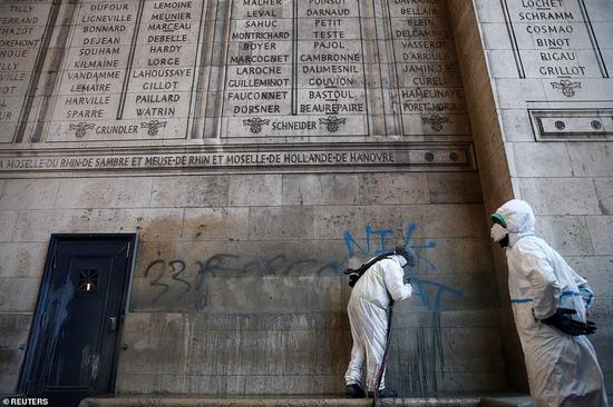  12月2日，在暴乱事件之后，工人们穿着防护服擦洗凯旋门上的涂鸦。（美联社）