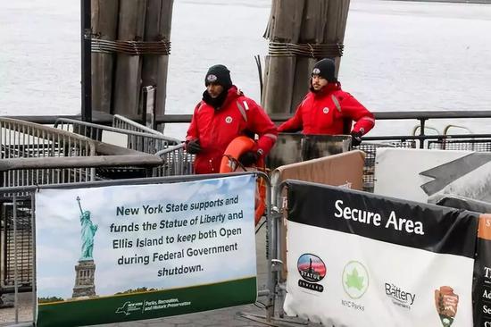 1月12日，在美国纽约的去往自由女神像的码头，工人在工作，旁边的告示写着“由于联邦政府停摆，纽约州政府资助其继续开放”。新华社记者王迎摄