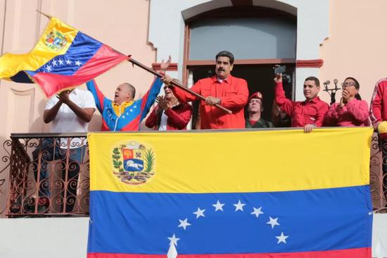 ▲1月23日，在委内瑞拉加拉加斯，委总统马杜罗（中）在参加群众集会时挥舞国旗。（新华社发）