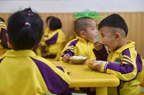 在福建省石狮市鹏博幼儿园，刚刚入园一个月的聪聪（右一）在吃饭。