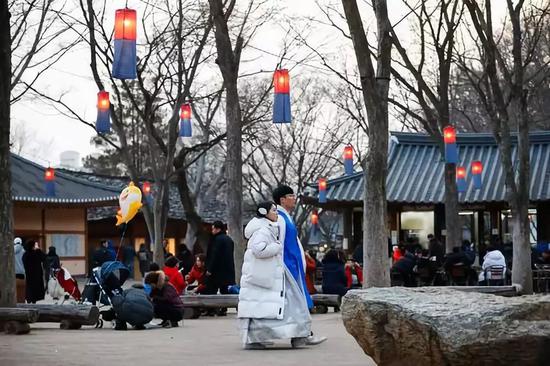 2月5日，一对年轻情侣身着韩服在韩国京畿道龙仁市的韩国民俗村参观。当日是农历新年第一天，不少韩国民众身着韩服来到韩国民俗村体验年俗。韩国民俗村有传统住宅260余座，再现了朝鲜半岛传统社会的风貌。在节假日期间安排丰富多彩的民俗游戏，供游客体验。新华社记者 王婧嫱摄