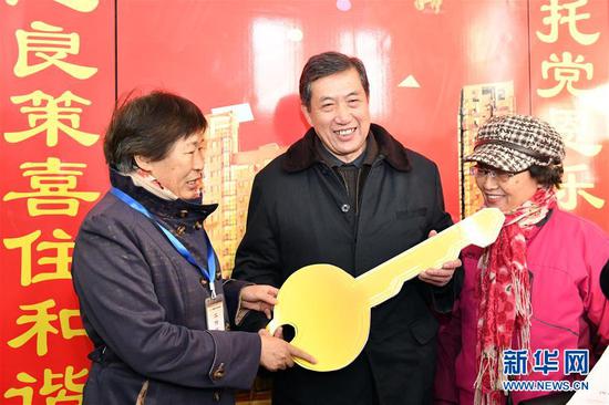 回迁居民迟明德（中）成为济南市槐荫区经十一路棚户区改造项目——和谐佳苑小区第一位办理回迁入住的居民（2018年12月20日摄）。新华社记者 郭绪雷 摄