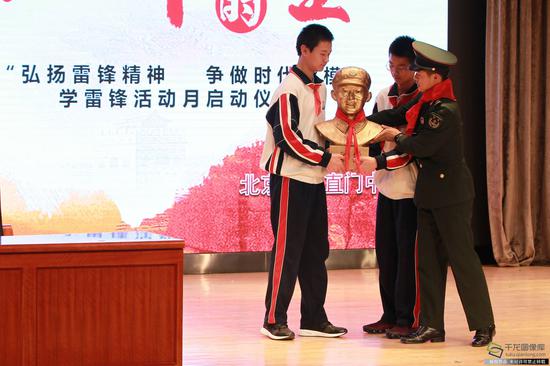 学雷锋活动日:学雷锋纪念日 北京在行动 雷锋班班长走进东直门中学讲述雷锋故事。第26届雷锋班班长张阳把雷锋塑像赠送给三校的同学们。徐鹏 摄。