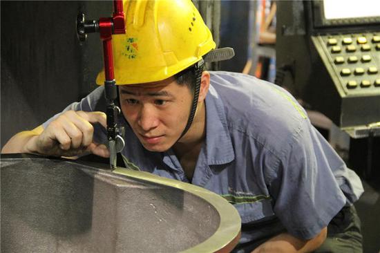  广西柳工机械股份有限公司高级技师庞淇文在生产车间检测零件（资料照片）。新华社发