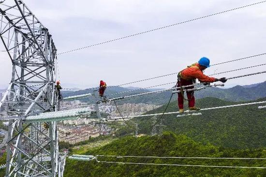 △2019年5月6日，浙江舟山电力工人在铁塔上架线