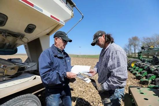 2019年4月，在美国艾奥瓦州卡斯县大西洋镇，农场主比尔·佩雷特（左）与其子布雷特核对种子的购买记录。（新华社记者王迎摄）