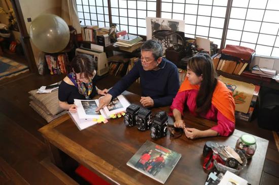 4月26日，在日本东京，秋山亮二（中）和女儿秋山都（右）在家中向记者介绍他的摄影作品资料。新华社记者杜潇逸摄