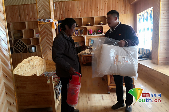 冲郎加（右）为村里的贫困户送去慰问品。本人供图