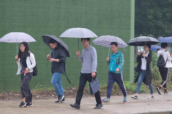 2019年5月19日，武汉一高校考点，参加2019湖北省事业单位公开招聘工作笔试的考生冒雨赶考。
