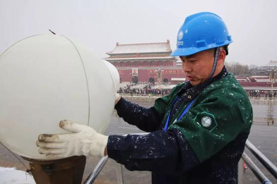  华灯班雪天巡视广场检修华灯。