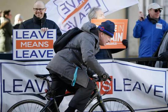 　2019年1月8日，在伦敦，英国前外交大臣鲍里斯·约翰逊骑车经过支持“脱欧”的示威者。新华社发（蒂姆·爱尔兰摄）