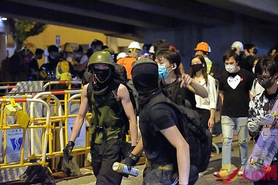 杨逸朗（左）在警总门外上齐装备准备对警总进行冲击。来源：香港文汇网（资料图片）