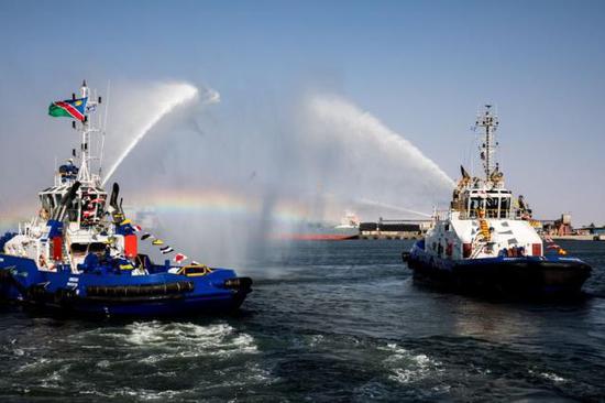（在纳米比亚沃尔维斯湾新集装箱码头竣工仪式上，消防船用水柱搭建起“水门”庆祝。 来源：新华社）