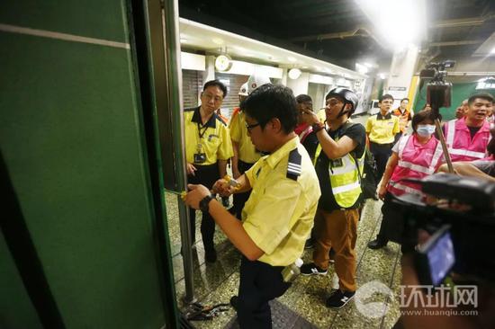  （23日晚，香港葵芳地铁站的港铁工作人员在关闭该站的闸门。摄：崔萌）