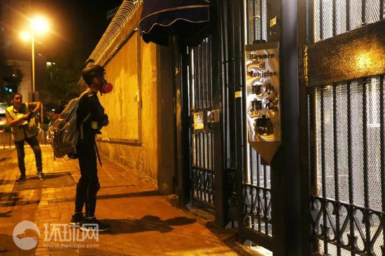  （23日晚，有头戴黑色头盔及面罩的黑衣人在葵涌警署前挑衅。摄：崔萌）