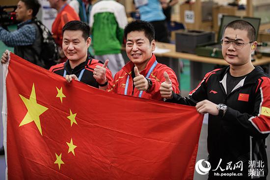 中国队选手金泳德（中）、谢振翔（左）、姚兆楠手持五星红旗，庆祝夺冠。