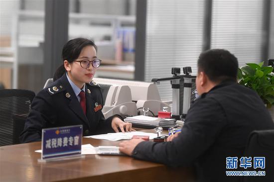 国家税务总局杭州市富阳区税务局工作人员(左)在富阳区行政服务中心减税降费专窗为纳税人办理业务(4月1日摄)。 新华社记者黄宗治摄