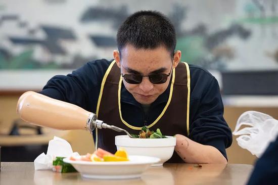 2019年10月24日，重庆西南医院康复楼，杜富国正在用辅助具吃饭。新京报记者 李凯祥 摄
