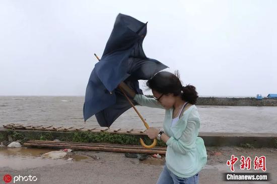 资料图：一记者手中拿着的雨伞被台风吹折。宁彪 摄  图片来源：IC photo