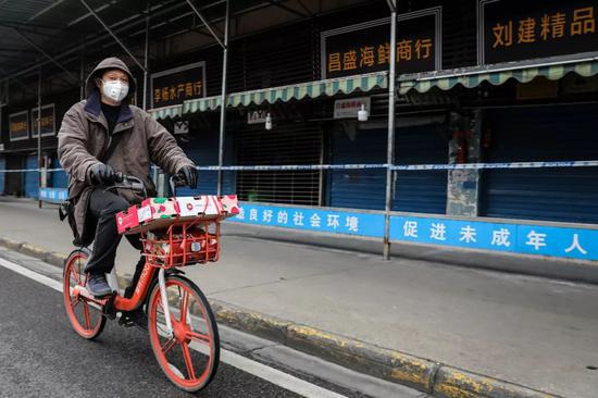  一位戴着口罩的市民骑车经过华南海鲜市场。