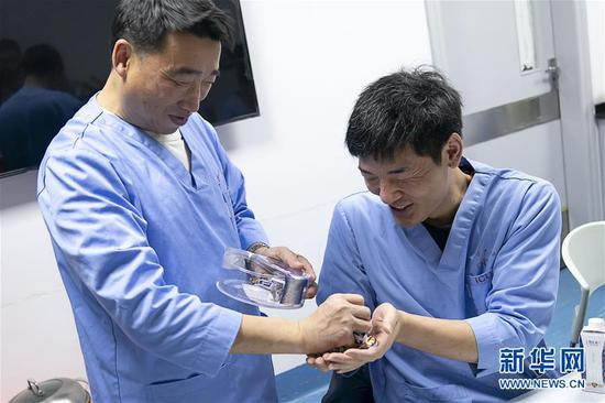  1月24日，武汉大学中南医院重症医学科主任彭志勇（左）给同事陈少峰分发糖果，作为年夜饭的“加餐”。 新华社记者 熊琦 摄