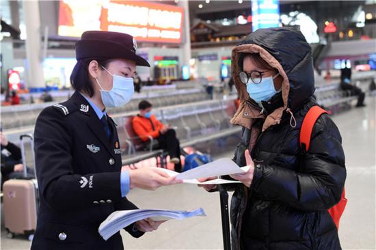在广西南宁东站，南宁铁路公安处女民警花子惠（左）将自己创作的疫情防控宣传漫画送给乘客（2月4日摄）。新华社记者 陆波岸 摄