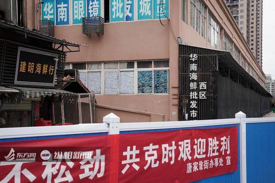 （图说：2020年3月30日，华南海鲜市场的临街店铺，被蓝色的围墙包围，店铺也被黑色的布料封挡。）