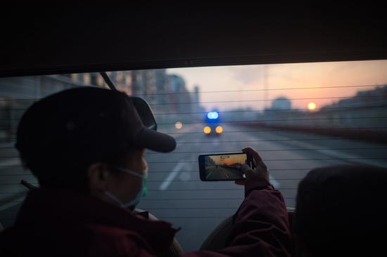 陕西国家紧急医学救援队队员在回程的车上拍摄武汉的日出（3月17日摄）。新华社记者 肖艺九 摄
