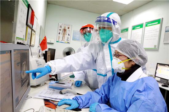  武汉大学中南医院影像科副主任张笑春（右一）和同事一起察看新冠肺炎患者CT影像（2月5日摄）。新华社发（高翔 摄）
